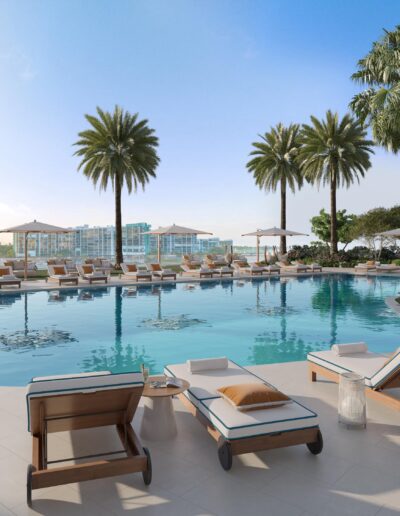 Luxury outdoor pool area with lounge chairs, palm trees, and city view in a waterfront Miami condo